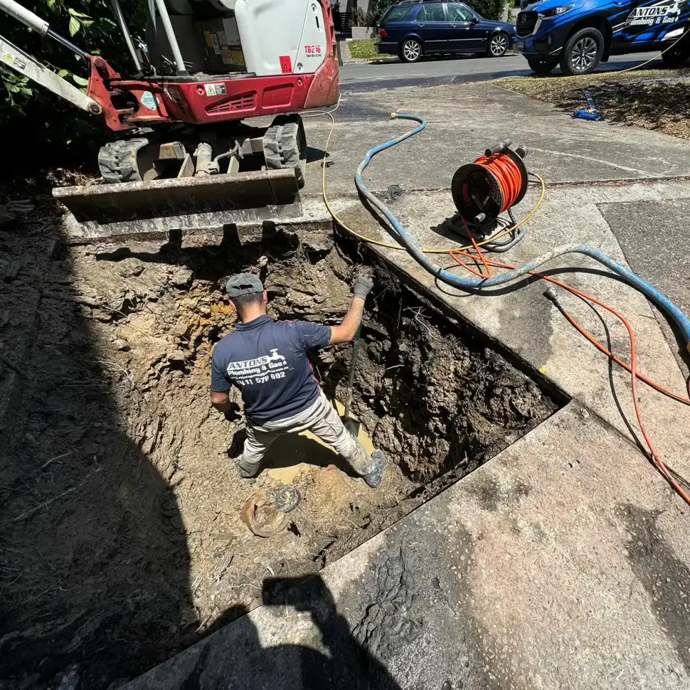 Plumber excavating underground pipework