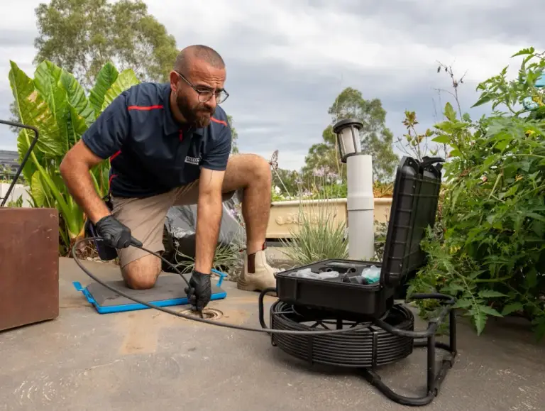 Plumber using a camera and monitor at a drain access opening