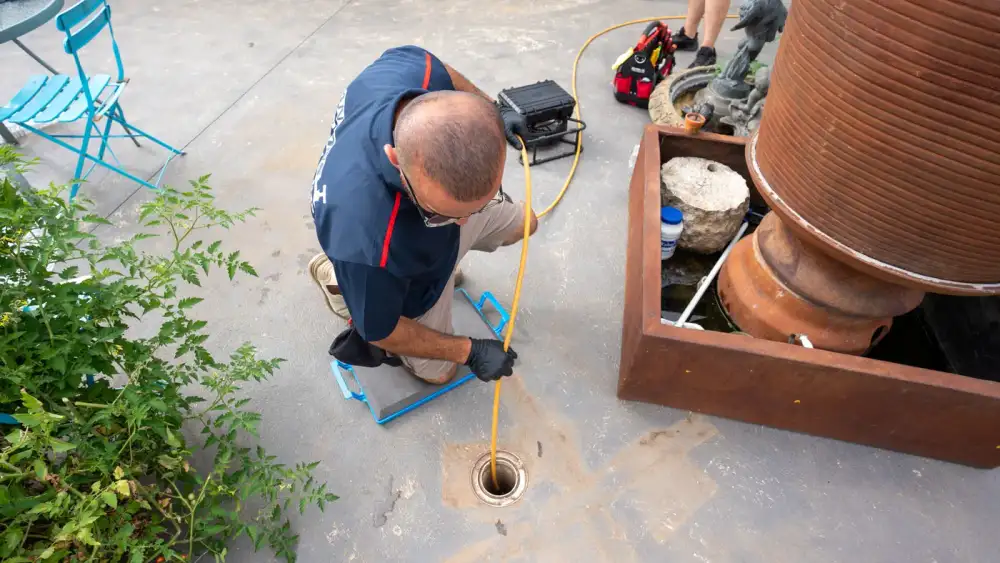 Overhead view of an Antons plumber feeding a line into a drain opening