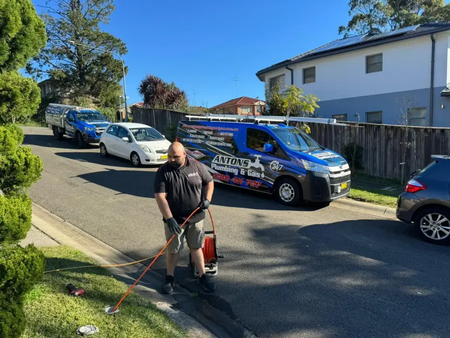 Antons plumber operating a drain hose beside service vehicles