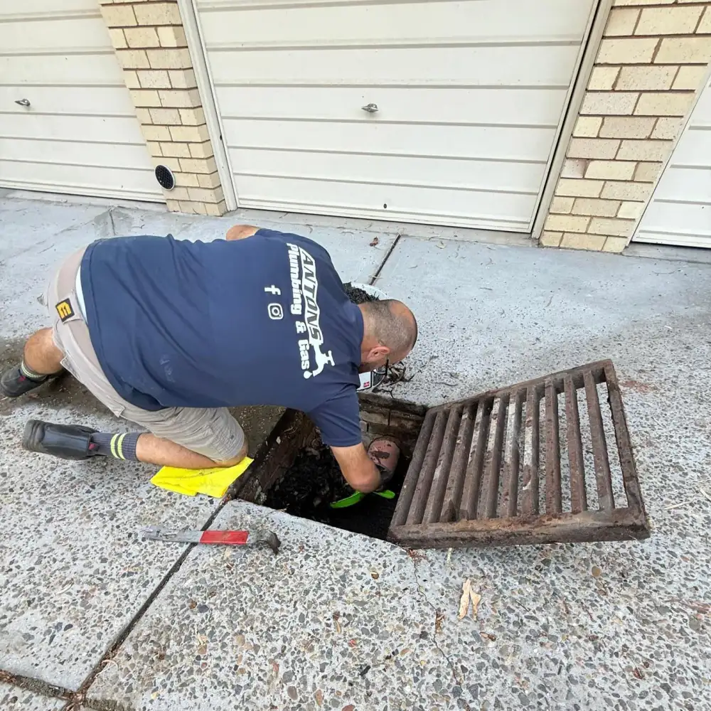 Plumber working at an open outdoor drain pit