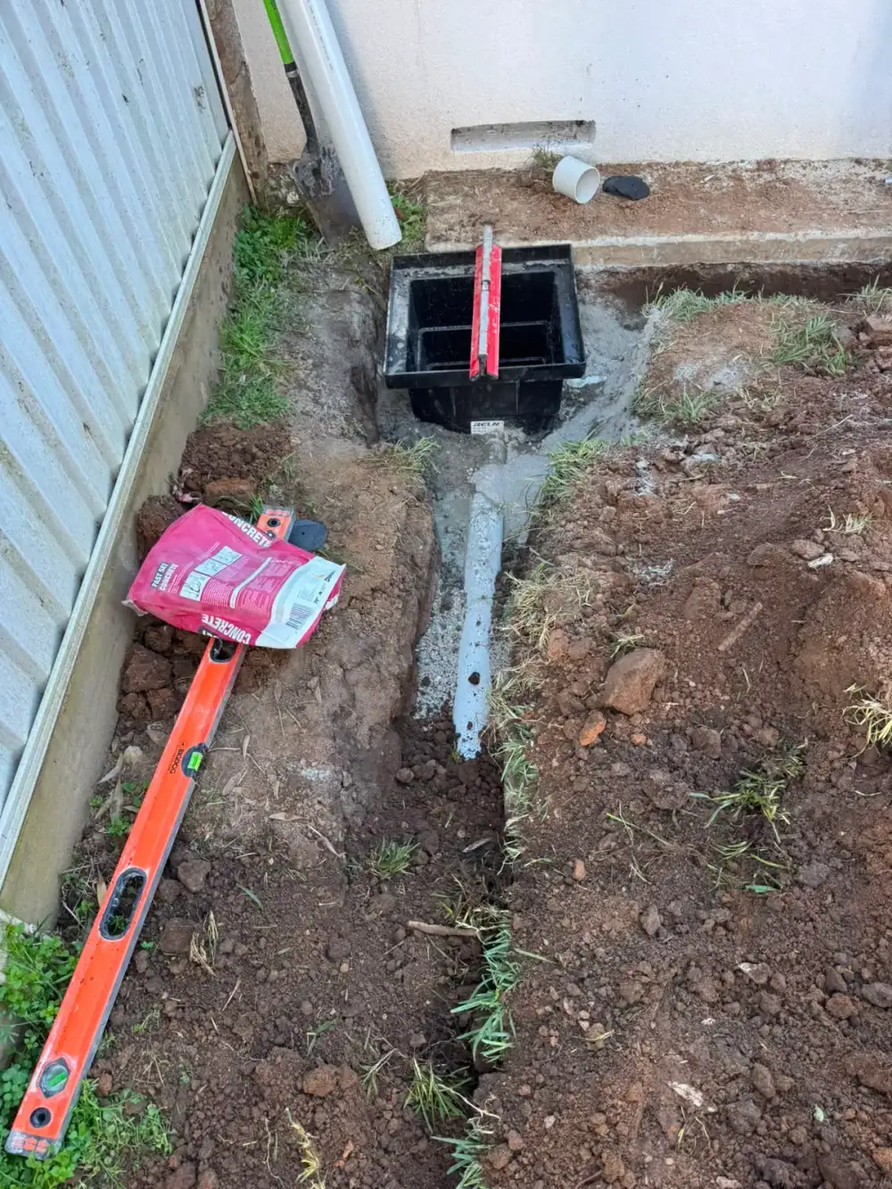 Stormwater pit and connecting pipe being installed beside a house