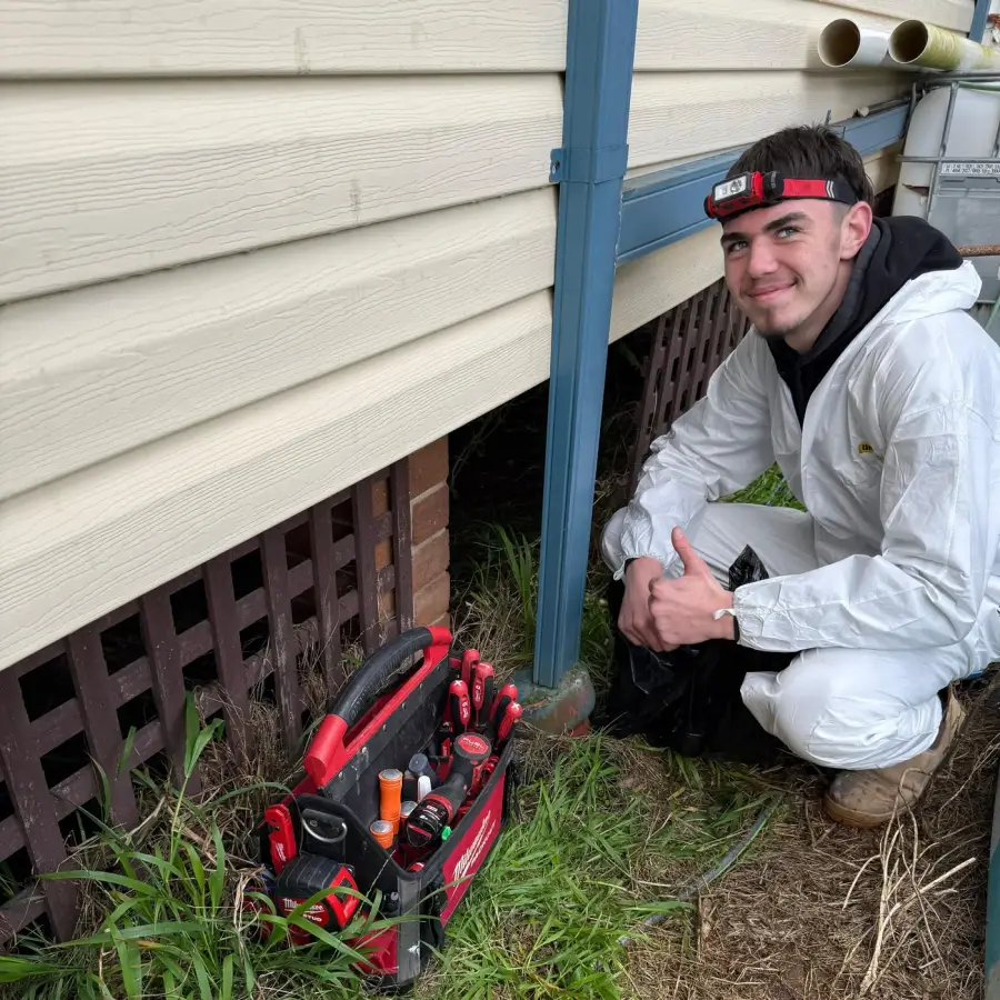 Antons technician beside a subfloor opening with a tool bag