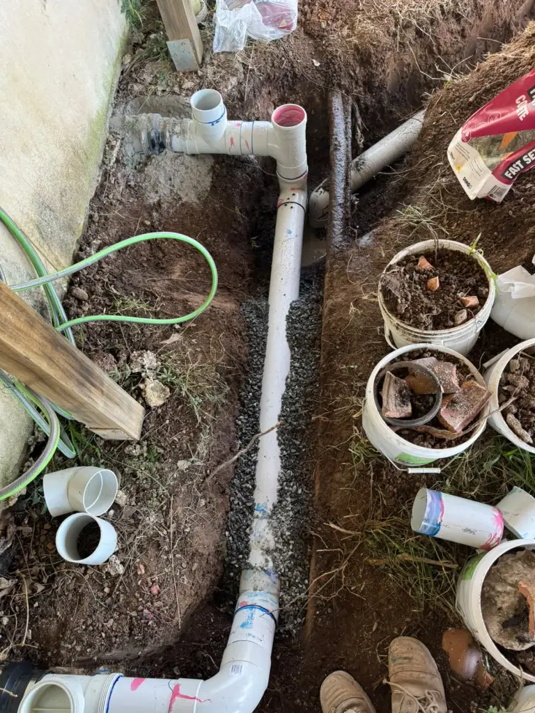 Replacement pipework and junctions exposed beside a house wall