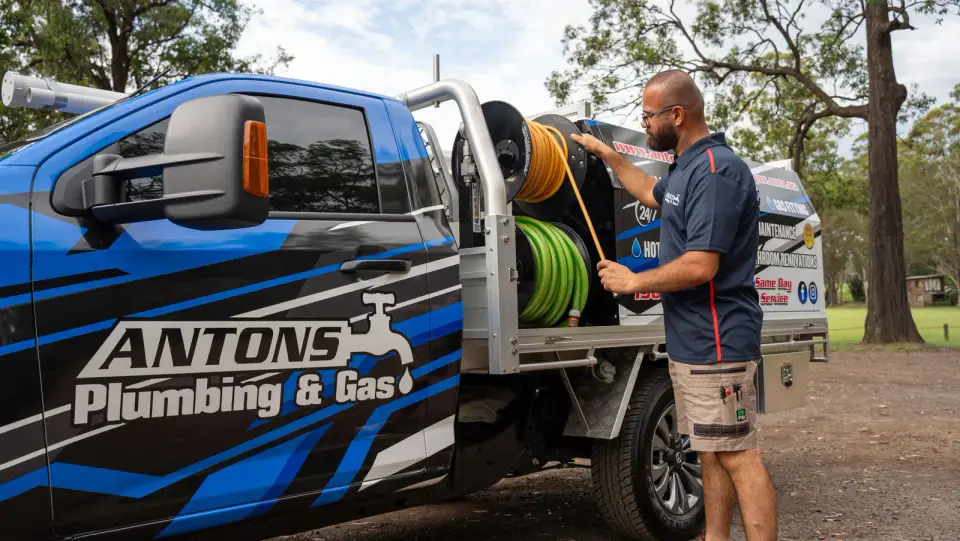 Technician beside a service vehicle fitted with drain-clearing equipment